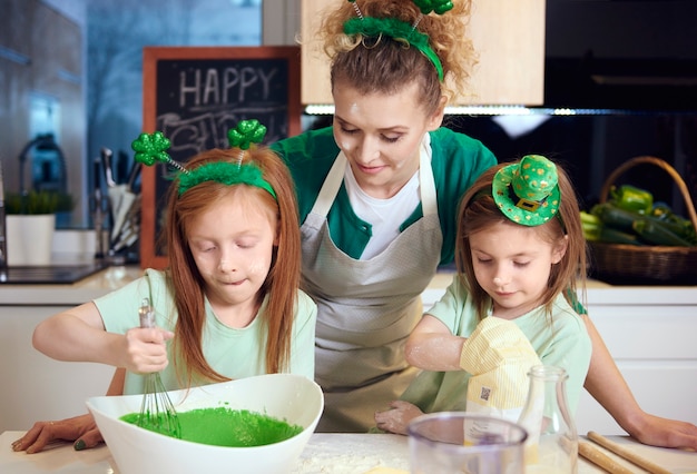 Children mixing fondant icing under mother's supervision