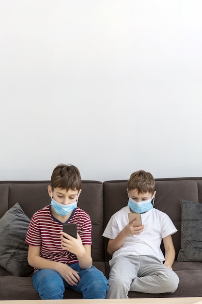 Children playing on smartphones while wearing medical masks