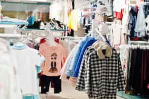 Free photo children's bright clothes hang on the display in the baby clothing store girls section