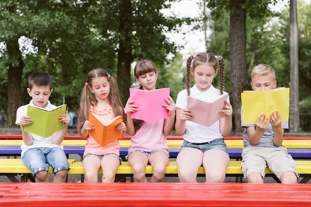 Free photo children sitting on bench and reading