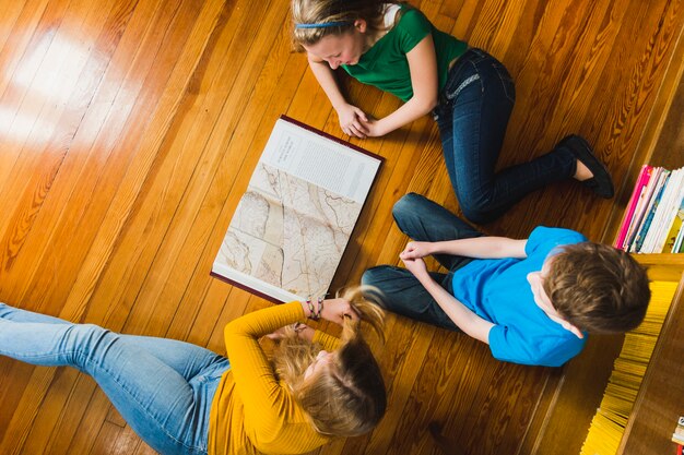 Children studying map sitting on floor 