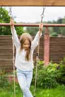 Free photo children on the swing. girl swinging on a swing in the yard. summer fun.