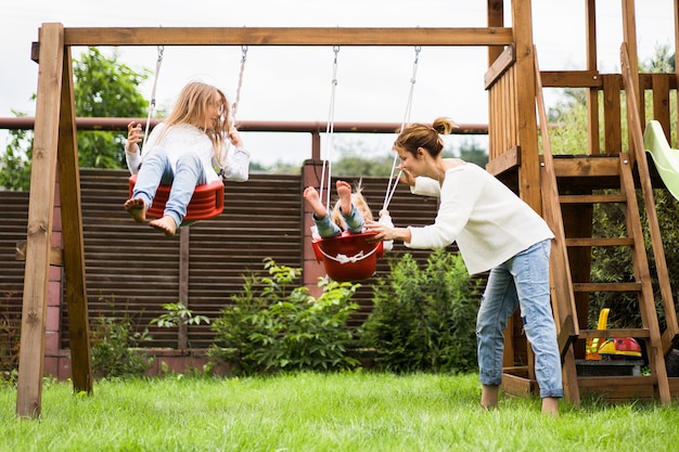 Free photo children on the swing. girls sisters swinging on a swing in the yard. summer fun.