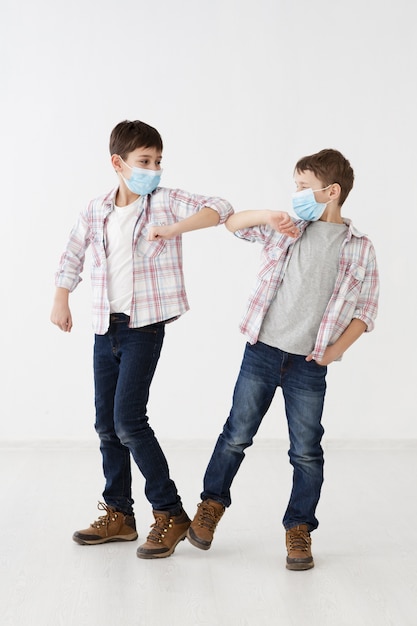 Children with medical masks demonstrating non-contact greetings