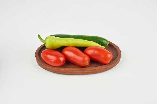 Chili peppers and tomatoes on a wooden board on the white.