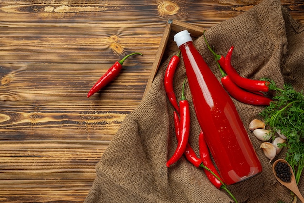 Chili sauce and peppers on dark wooden surface