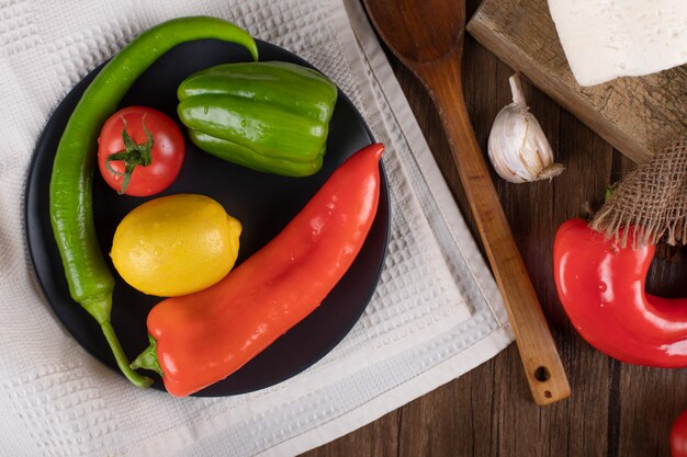 Chilies, tomato and lemon in a black plate