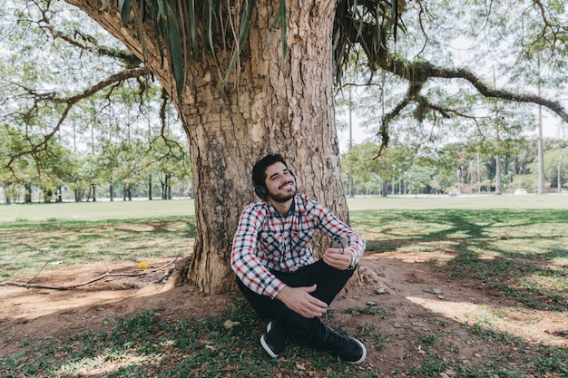 Chilling man in headphones under tree