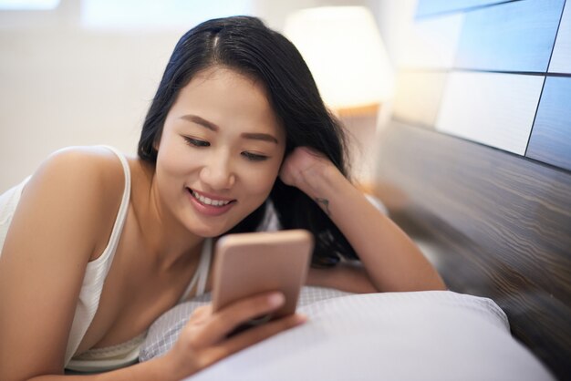 Chilling woman in bed using phone