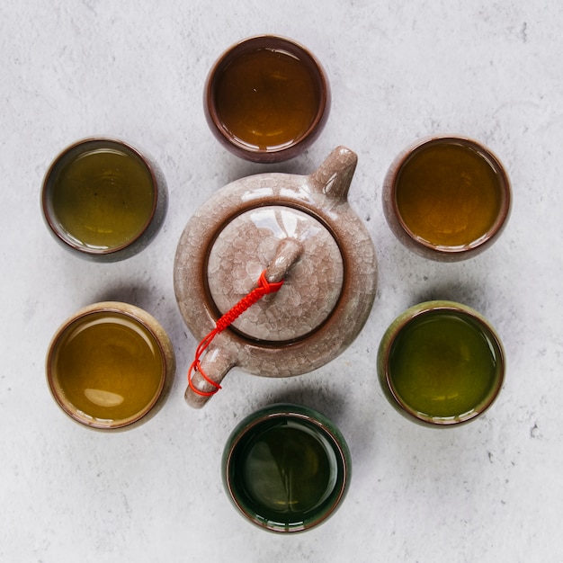 Chinese clay ceramic teapot surrounded with herbal teacup on backdrop