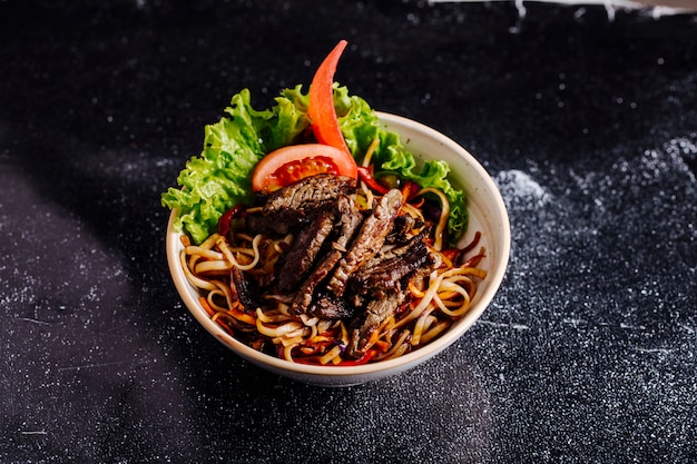 Free Photo chinese noodles inside bowl with chopped steak, tomato slices and lettuce.