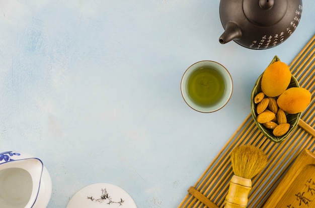 Free photo chinese tea set with dried fruits and brush on white textured background