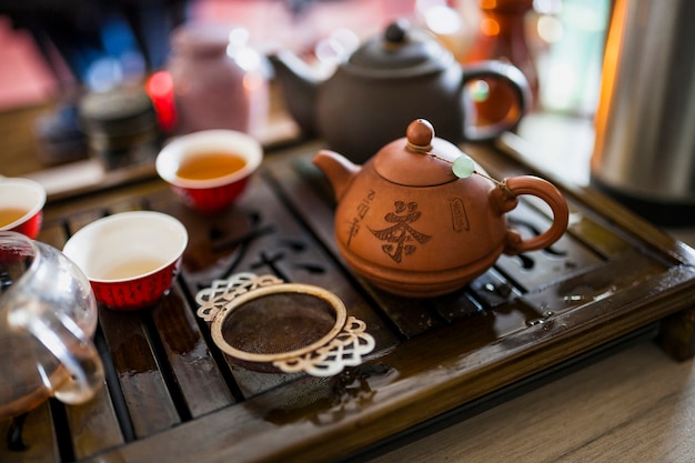 Chinese tea set with metallic strainer on wooden tray