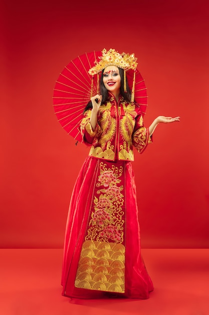 Free Photo chinese traditional graceful woman at  over red background. beautiful girl wearing national costume. chinese new year