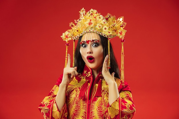 Free photo chinese traditional graceful woman at studio over red background.