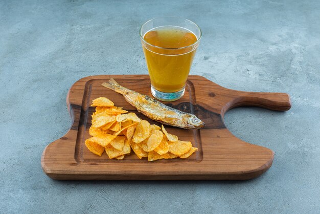 Chips, fish and glass of beer on a board , on the marble background. 