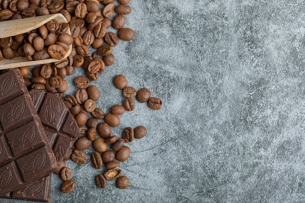 Chocolate bars with coffee beans on gray.