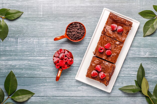 Free photo chocolate brownie cake dessert slices with raspberries and spices,top view