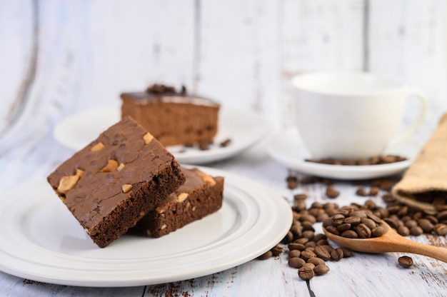 Chocolate brownies on a white plate and coffee beans on a wooden spoon.