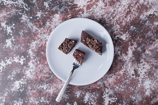 Free photo chocolate brownies in a white plate, top view.