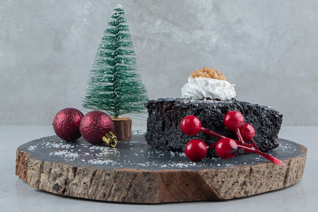 Free photo chocolate cake and christmas decorations on a wooden board on marble background.