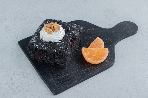 Chocolate cake and marmalades on a black board on marble background.