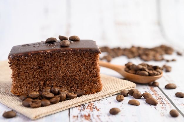 Chocolate cake on the sack with coffee beans on a wooden table.