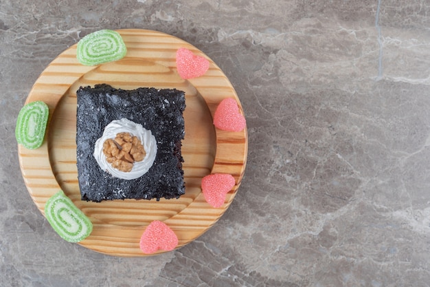 Chocolate cake surrounded with jelly sweets on a platter on marble surface