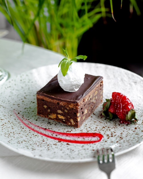 Free photo chocolate cake with nuts, ice cream on top and strawberries 1