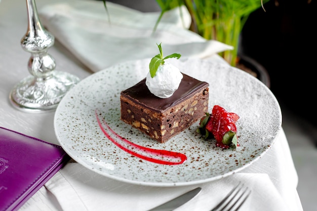 Free photo chocolate cake with nuts, ice cream on top and strawberries