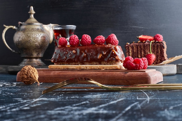 Chocolate cake with raspberries on a wooden board. 