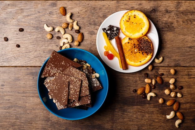 Chocolate candies orange cinnamon and nuts on wood