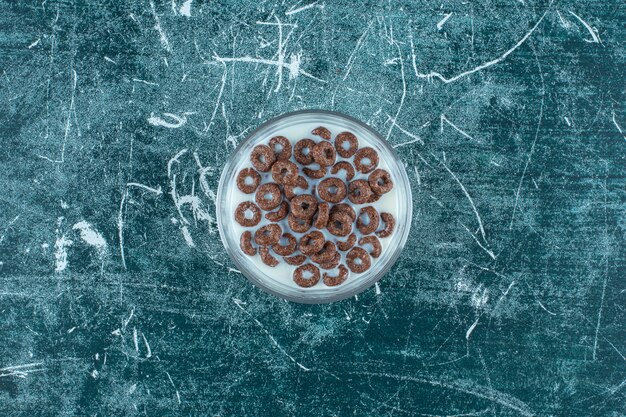 Chocolate cereal flakes rings with milk in a glass bowl , on the blue background. High quality photo