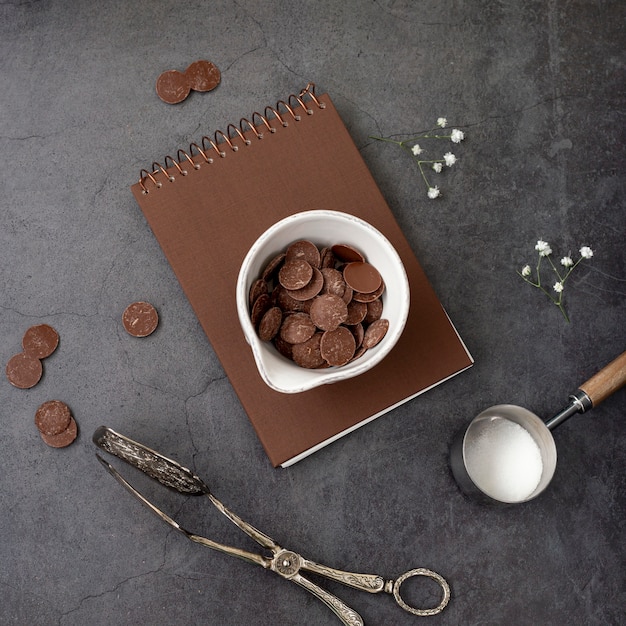 Free photo chocolate chips on a brown notebook on a grey background