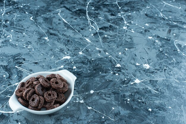 Chocolate coated corn ring in a bowl, on the marble background. 