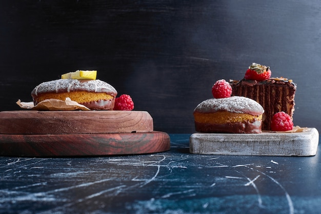 Free photo chocolate cookies and cake slices on wooden board.