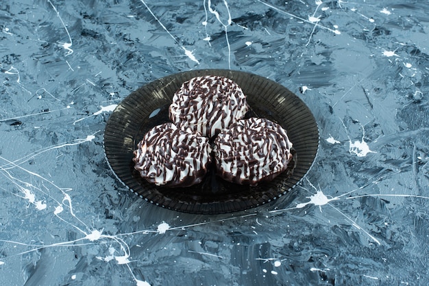 Free photo chocolate cookies on glass plate on blue.