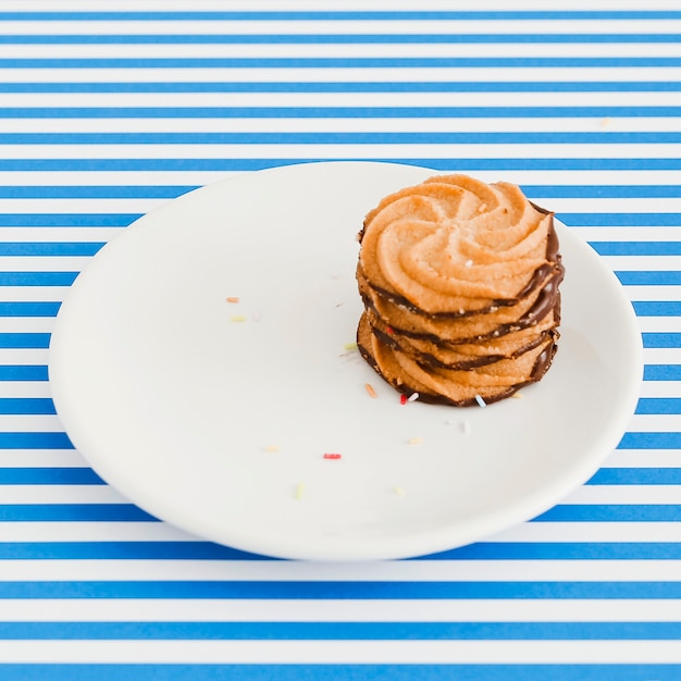 Chocolate cookies on plate over the blue and white stripes background