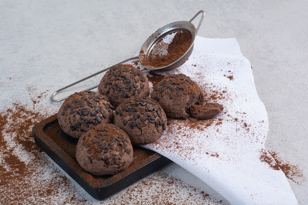 Free photo chocolate cookies with cocoa powder on wooden plate