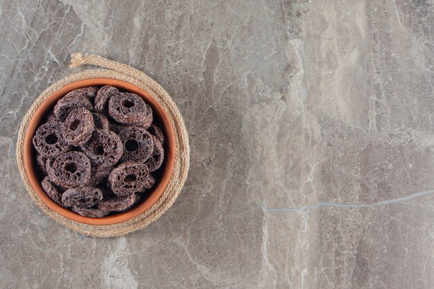 Chocolate corn rings in a bowl on trivet on blue.