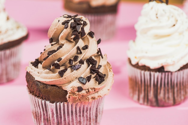 Chocolate cupcake with swirled butter cream on pink background