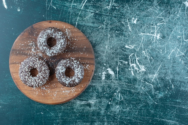 Free Photo chocolate donuts on the board , on the blue background. high quality photo