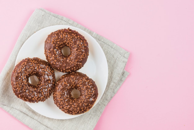 Free photo chocolate donuts on plate on gray material