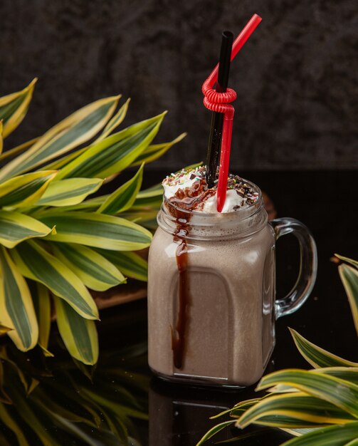 chocolate drink in a mason jar with whipped cream, sprinkles and chocolate syrop on top