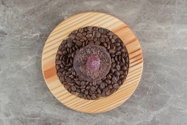 Chocolate frosted cake and coffee beans on wooden plate