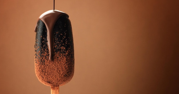 Chocolate ice cream on a stick and liquid chocolate covered it Different chocolate textures on brown background