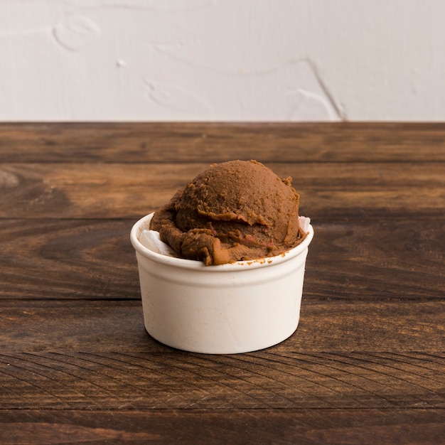 Chocolate ice cream in white bowl on wooden surface