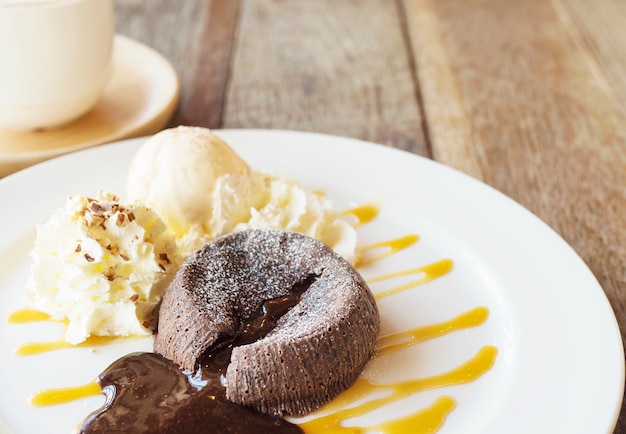 Free Photo chocolate lava cake in white plate with coffee cup on old wooden table