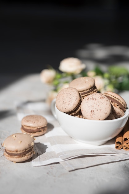 Free photo chocolate macaroons in ceramic bowl over the napkin