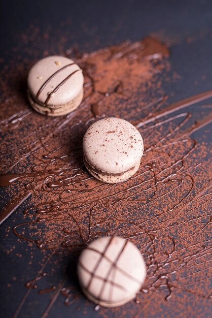 Chocolate powder and syrup over the macaroons on black backdrop